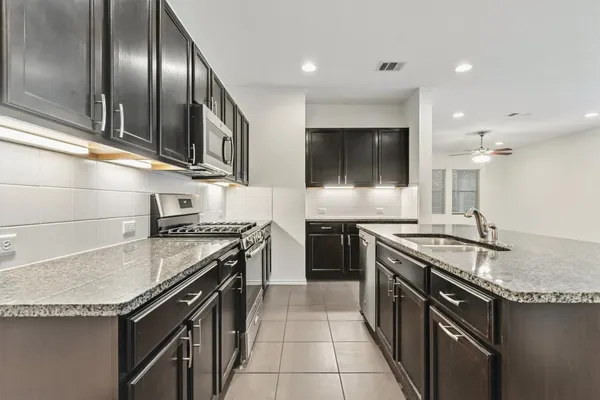 a kitchen with stainless steel appliances granite countertop a stove a sink and a microwave