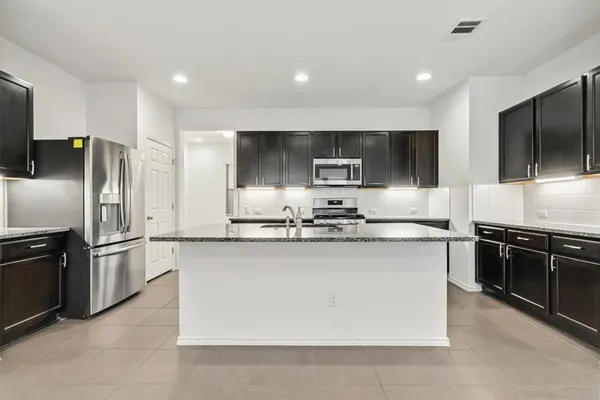 a kitchen with stainless steel appliances granite countertop a stove a sink and a refrigerator