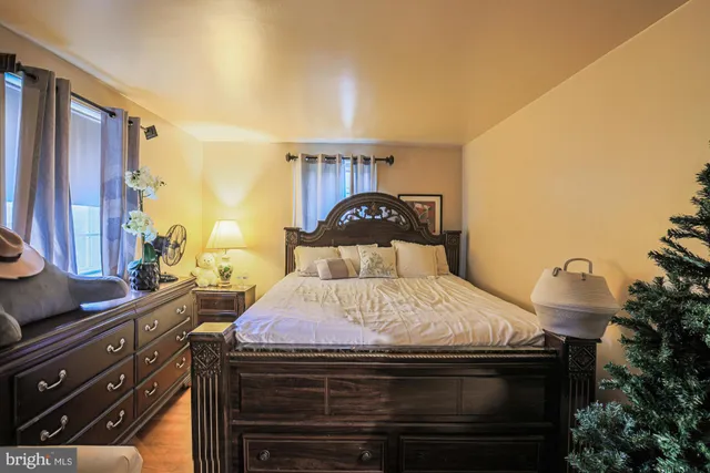 a bedroom with a bed and a potted plant on the dresser