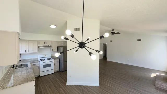 a kitchen with stainless steel appliances granite countertop a refrigerator a stove and a wooden floors