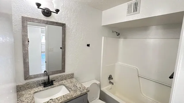 a bathroom with a granite countertop sink a toilet and shower