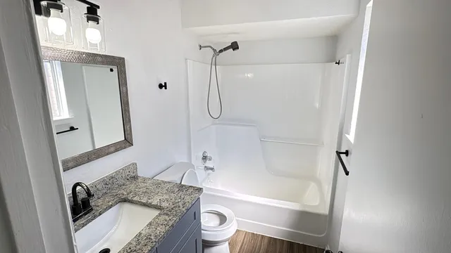 a bathroom with a granite countertop sink toilet mirror and shower