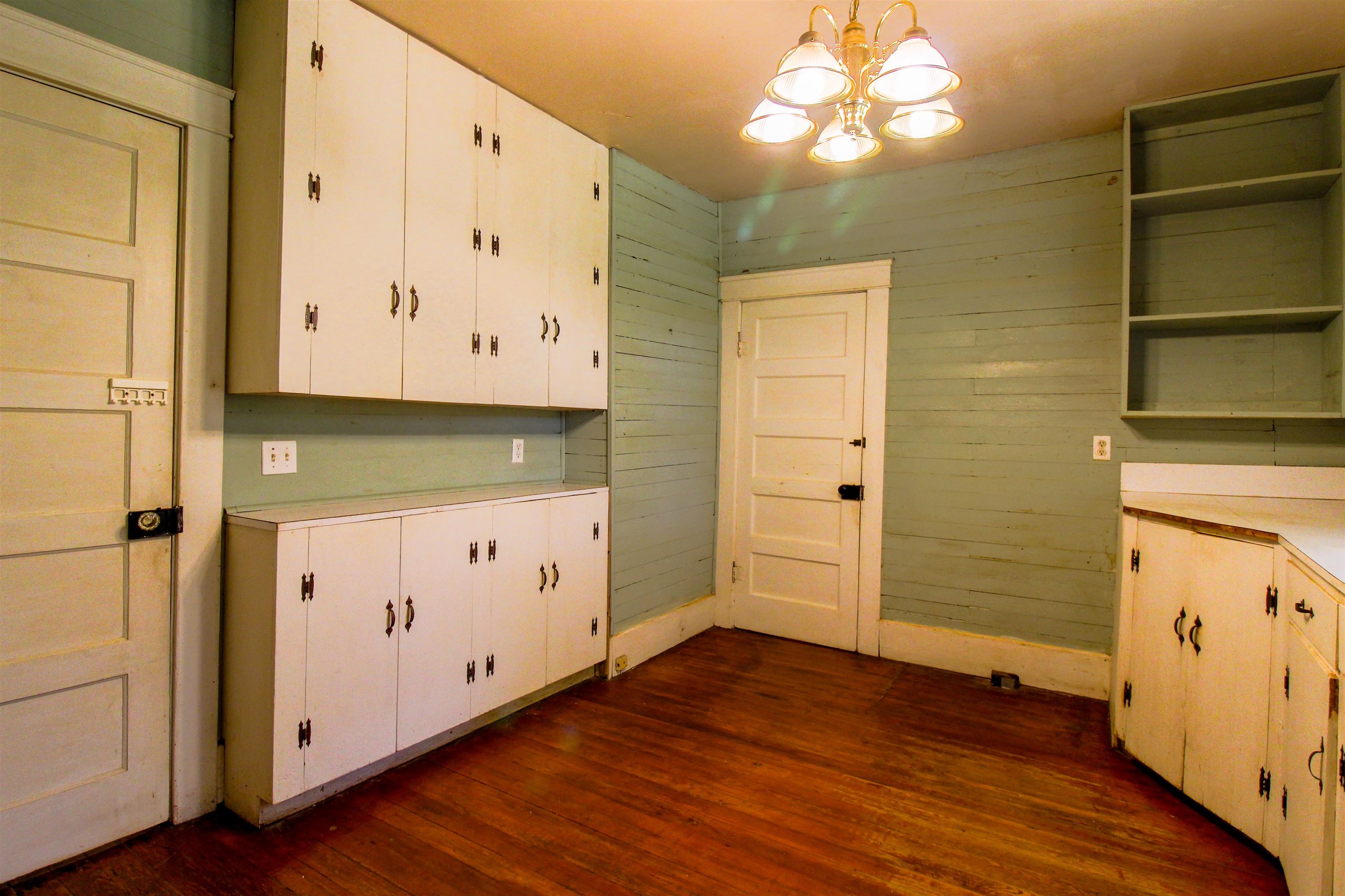 2440 Edith-Nankipoo Road Ripley, TN 38063 - Photo 7 of 27 Kitchen featuring open shelves, light countertops, dark wood-type flooring, white cabinets, and wooden walls
