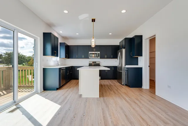 a kitchen with stainless steel appliances granite countertop a refrigerator a stove top oven a sink dishwasher and white cabinets with wooden floor