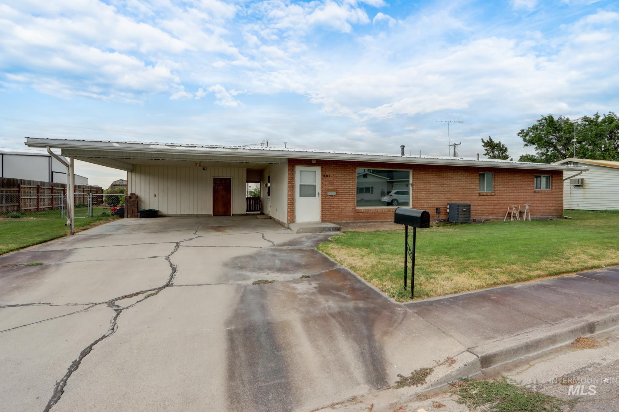 801 Thompson Avenue Nyssa, OR 97913 - Photo 45 of 46 Brick-front residence featuring a carport, concrete driveway, and a front yard with established grass