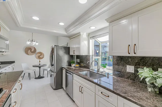a kitchen with granite countertop a sink stainless steel appliances and cabinets