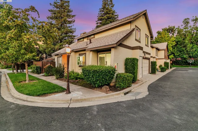 a view of a white house with a small yard and potted plants