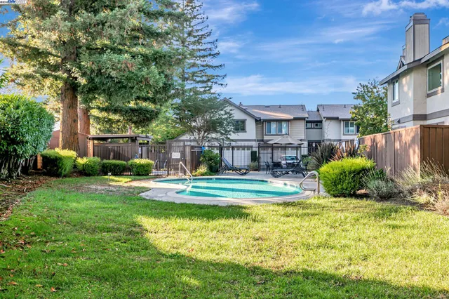 a view of a house with a yard and table and chairs under an umbrella