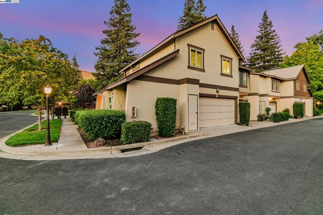 a view of a white house with a yard and potted plants