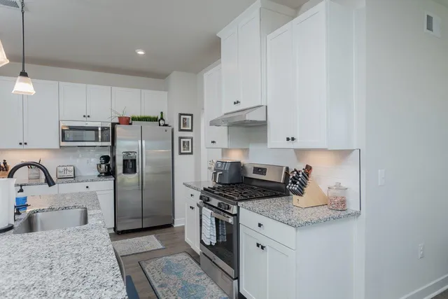 a kitchen with stainless steel appliances white cabinets and a refrigerator