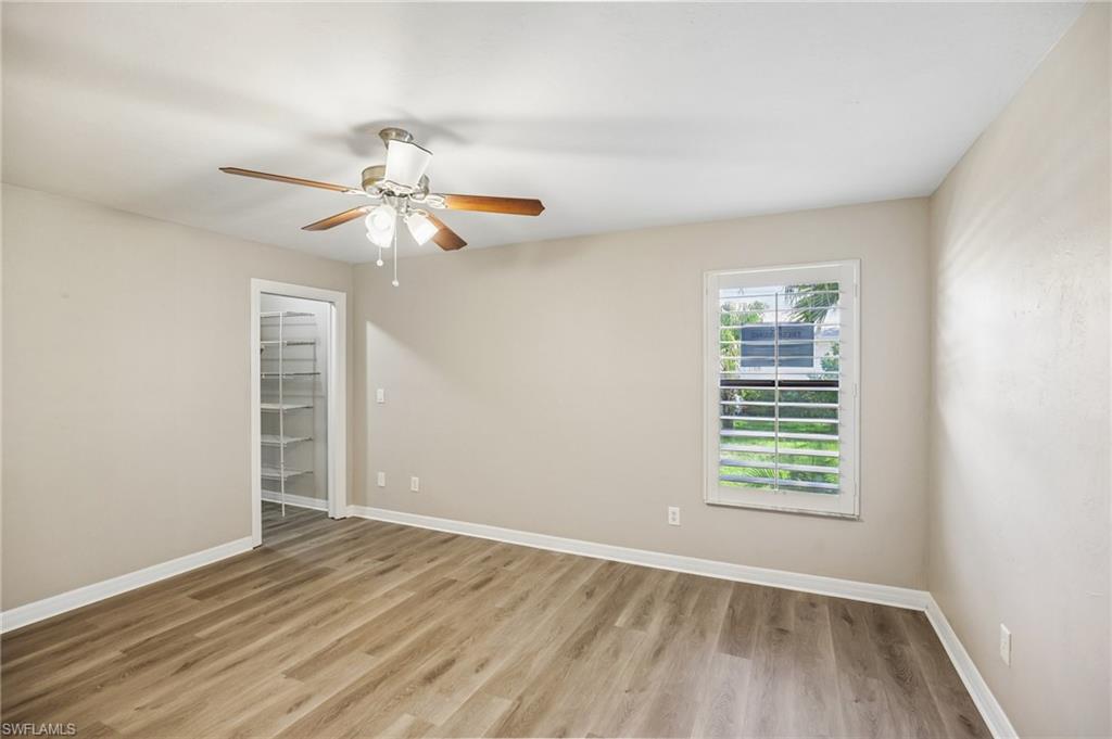 1937 Princess Court Naples, FL 34110 - Photo 32 of 42 an empty room with wooden floor chandelier fan and windows