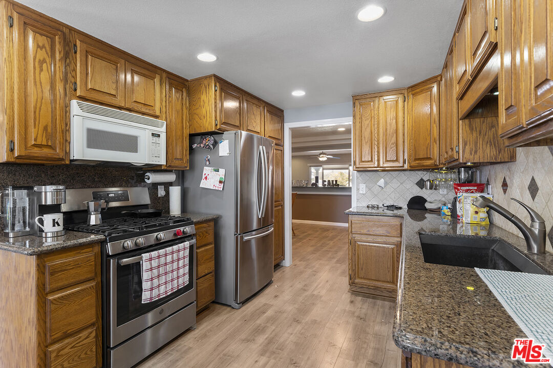 8391 Hillside Road Rancho Cucamonga, CA 91701 - Photo 19 of 51 a kitchen with stainless steel appliances granite countertop a stove top oven a sink dishwasher and cabinets with wooden floor