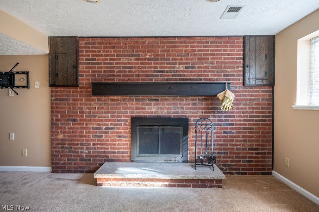 3601 River Road Vienna, WV 26105 - Photo 26 of 40 Detailed view of a brick fireplace, carpet floors, and a textured ceiling
