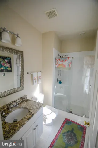 a bathroom with a granite countertop sink and a shower
