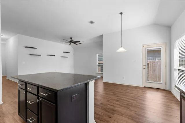a kitchen with a table a refrigerator and wooden floor
