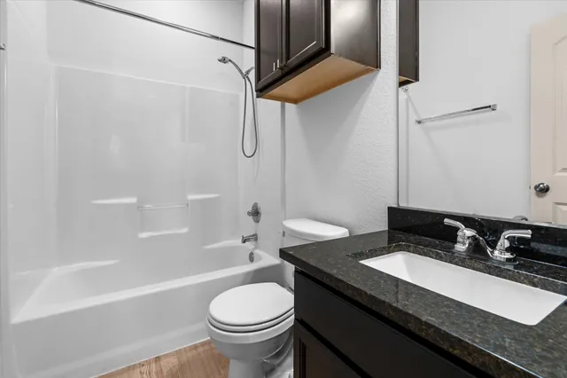 a bathroom with a granite countertop sink toilet and shower