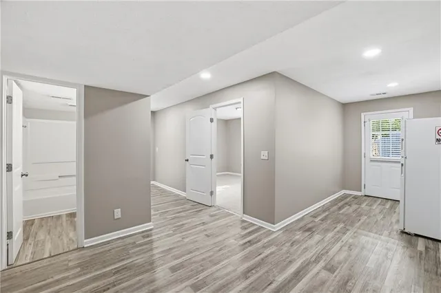 a view of an empty room with wooden floor and a bathroom