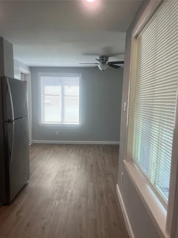 a view of an empty room with a window and wooden floor