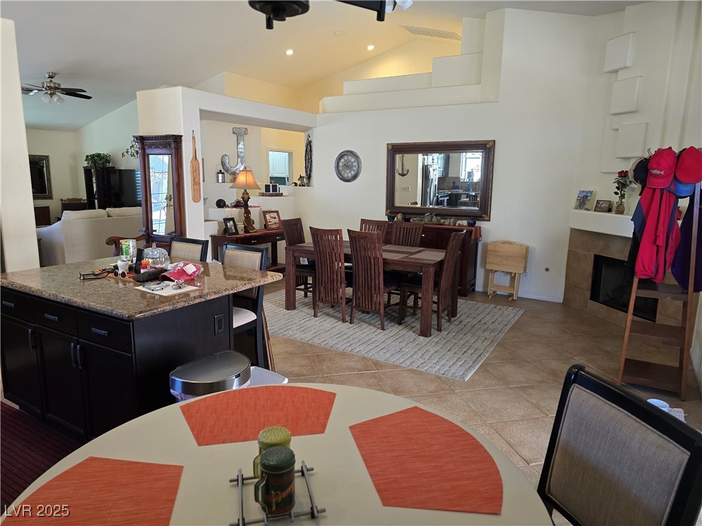 853 Rusty Anchor Way Henderson, NV 89002 - Photo 7 of 76 Dining space featuring light tile patterned flooring, a wealth of natural light, a tile fireplace, a ceiling fan, and lofted ceiling