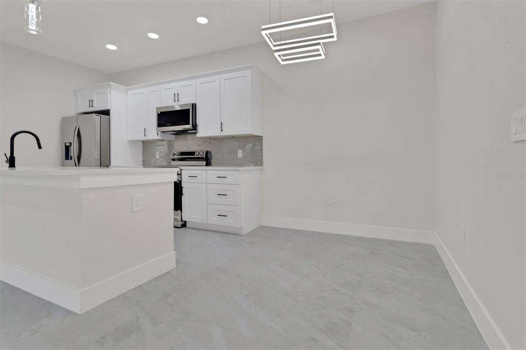 4501 15th Street Southwest Lehigh Acres, FL 33973 - Photo 11 of 40 a kitchen with stainless steel appliances a refrigerator sink and white cabinets