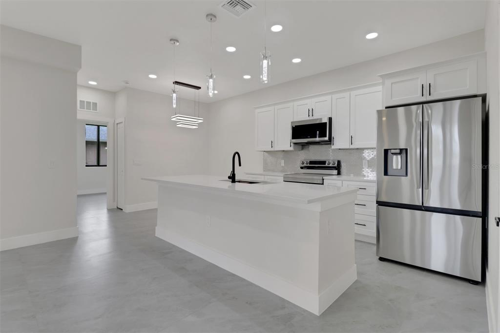 4501 15th Street Southwest Lehigh Acres, FL 33973 - Photo 29 of 40 a kitchen with white cabinets and stainless steel appliances