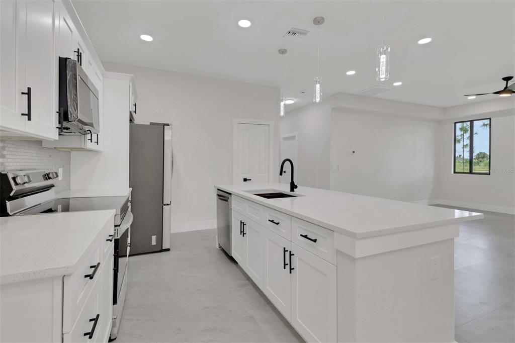 4501 15th Street Southwest Lehigh Acres, FL 33973 - Photo 30 of 40 a kitchen with stainless steel appliances a sink a stove a refrigerator and cabinets