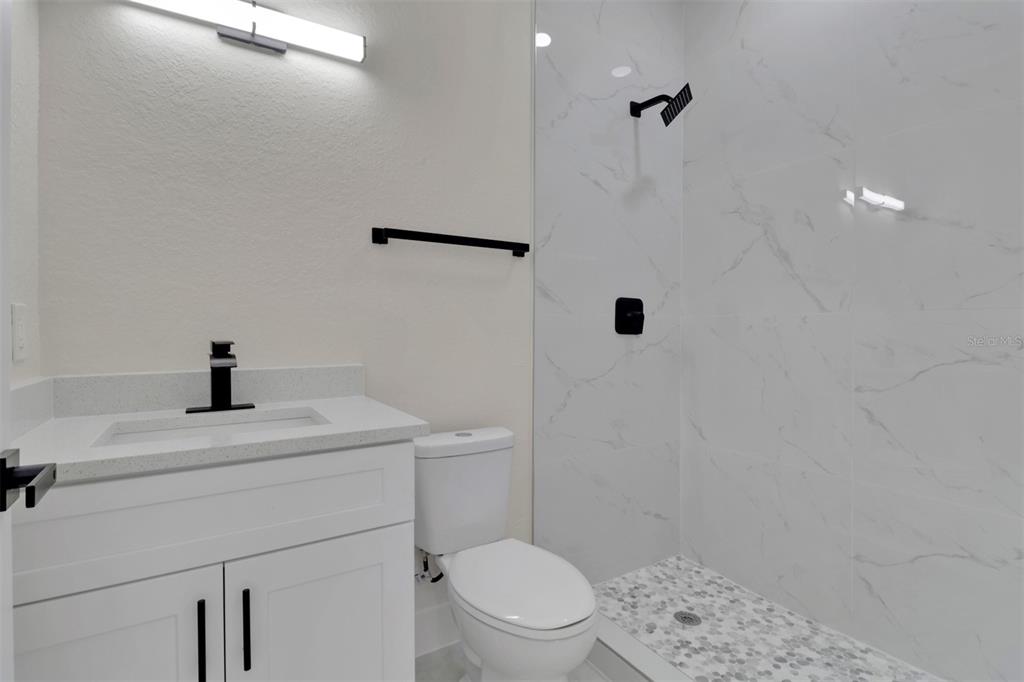 4501 15th Street Southwest Lehigh Acres, FL 33973 - Photo 38 of 40 a bathroom with a toilet a sink a shower and mirror