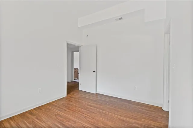 a view of an empty room with wooden floor and closet