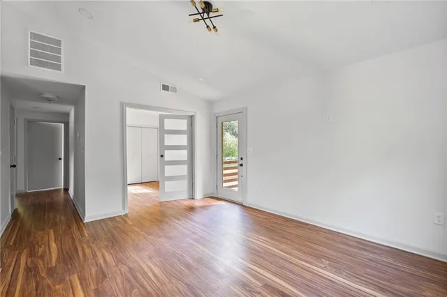 a view of an empty room with a window and wooden floor