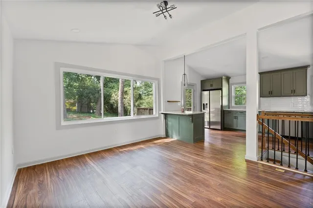 a view of an empty room with a window and wooden floor