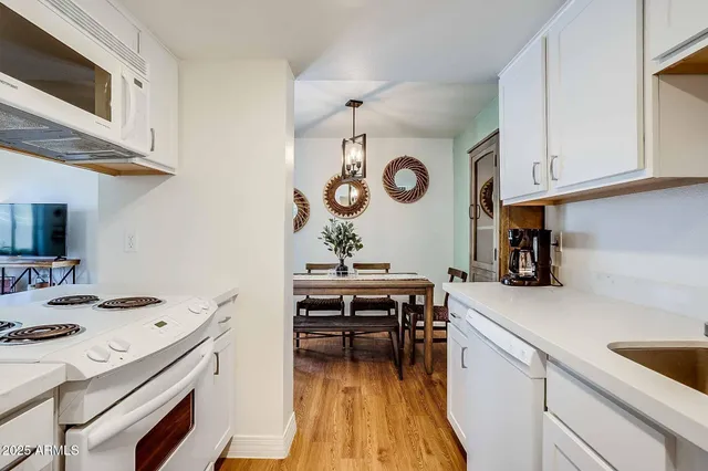 a kitchen with stainless steel appliances a sink a stove and white cabinets