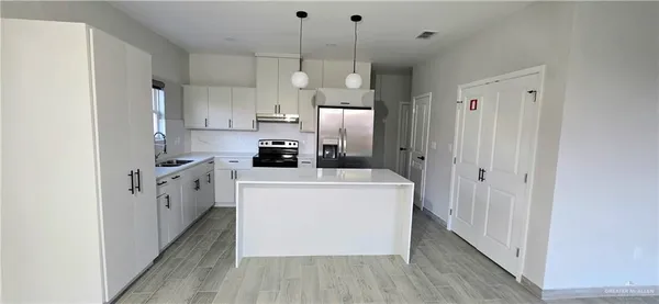 a view of a kitchen with a sink dishwasher a refrigerator and wooden floor