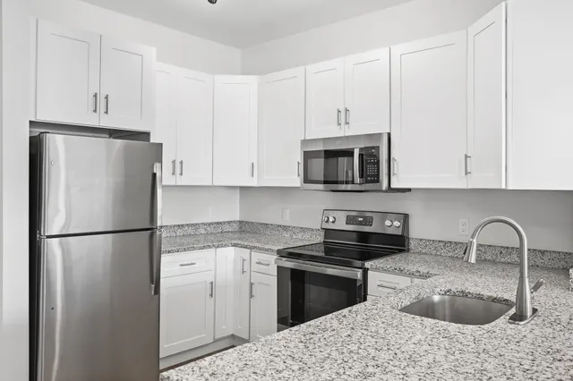 a kitchen with stainless steel appliances granite countertop a sink stove and refrigerator