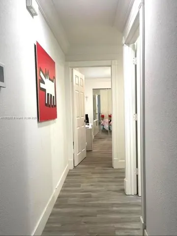 a hallway with wooden floor chandelier and living room