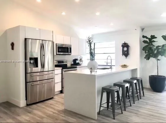 a kitchen with kitchen island white cabinets and stainless steel appliances