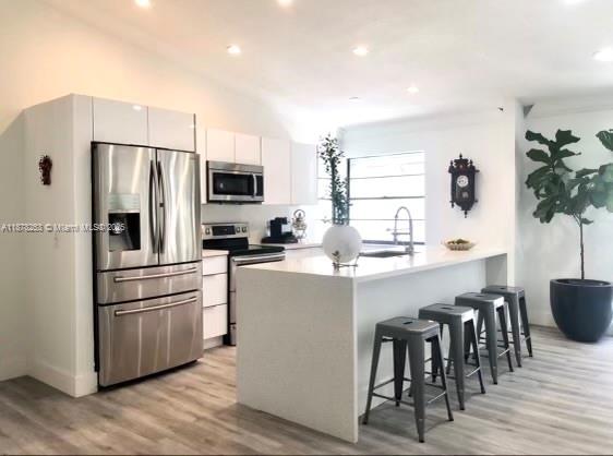 23304 Southwest 58th Avenue, Unit B Boca Raton, FL 33428 - Photo 3 of 32 a kitchen with kitchen island white cabinets and stainless steel appliances