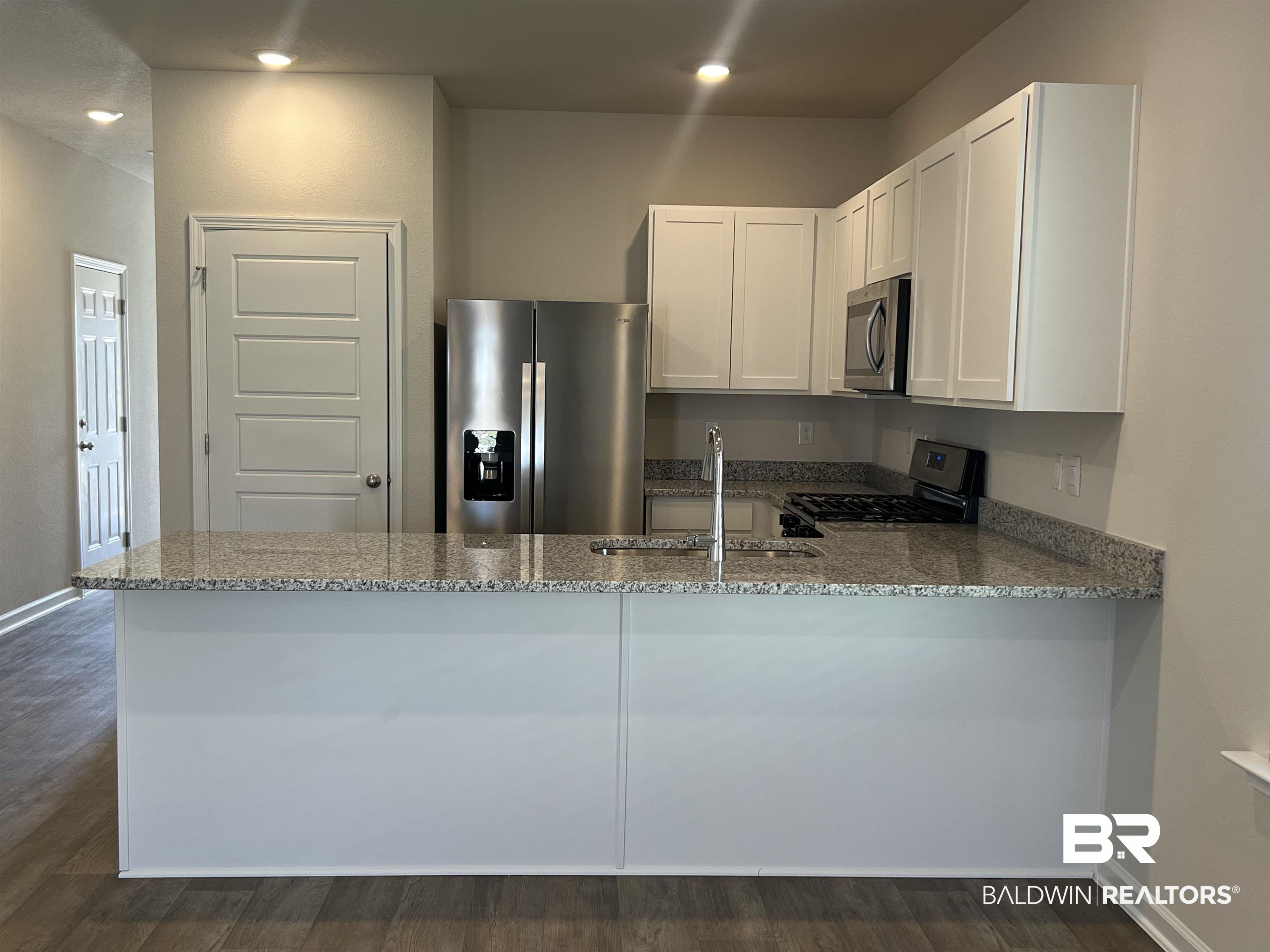 12829 Patriot Way Daphne, AL 36527 - Photo 14 of 38 Kitchen with kitchen peninsula, white cabinetry, dark wood-type flooring, and appliances with stainless steel finishes