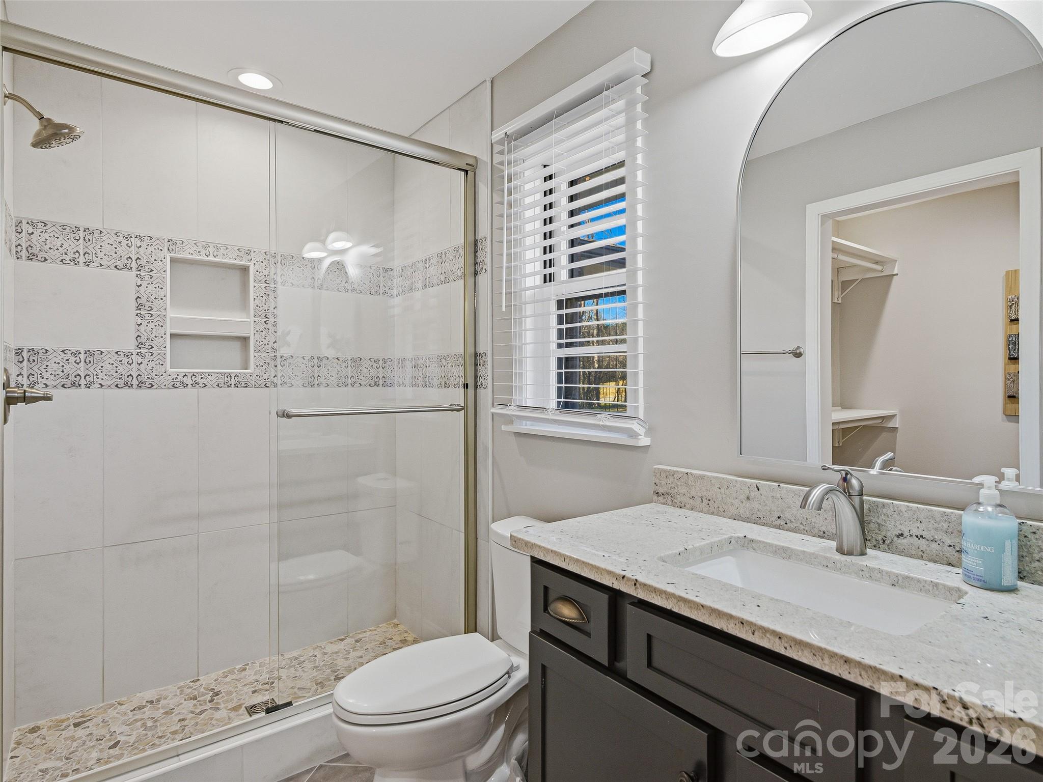 3869 Crab Creek Road Penrose, NC 28766 - Photo 13 of 19 a bathroom with a granite countertop sink a toilet a mirror and shower