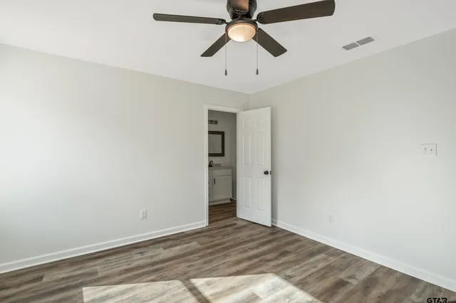 a view of a room with a ceiling fan and wooden floor