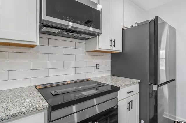 a kitchen with stainless steel appliances granite countertop a refrigerator and a stove