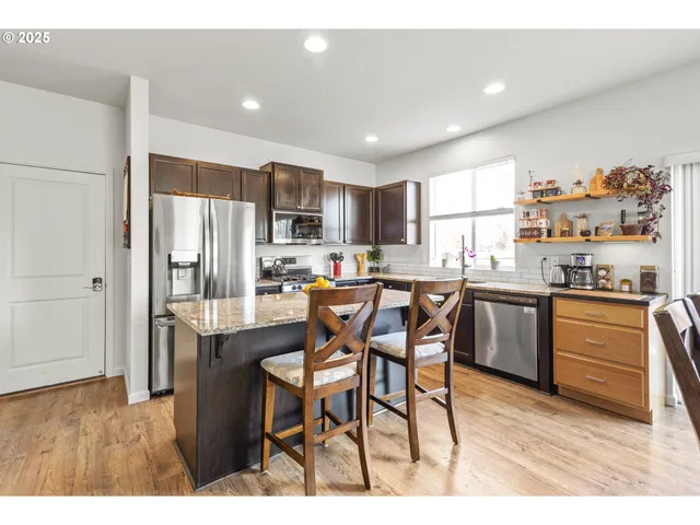 a kitchen with stainless steel appliances a refrigerator a stove a sink dishwasher with a dining table and chairs