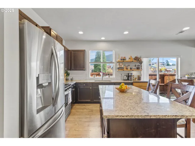 a kitchen with stainless steel appliances granite countertop a refrigerator a stove and a sink