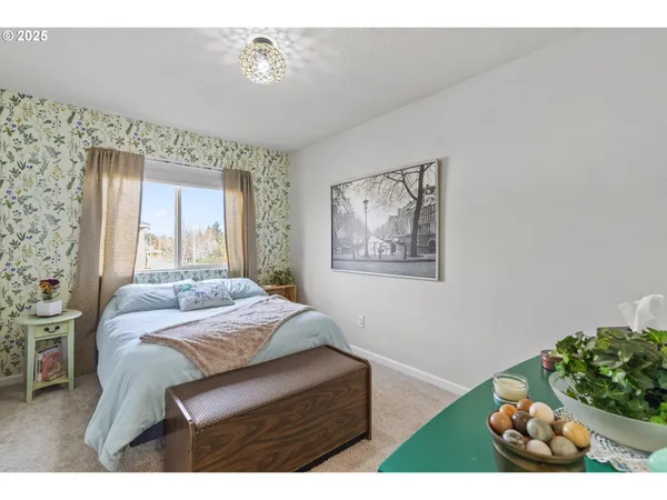 a bedroom with a bed painting on wall and a large window