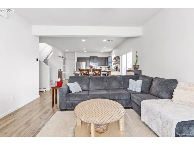 a living room with furniture and a dining table with wooden floor