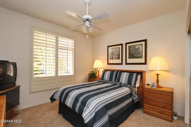 a bedroom with a bed next to a window with a flat screen tv