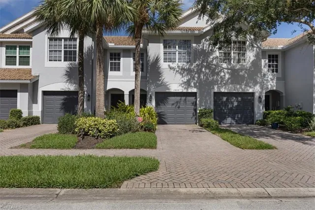 a front view of a house with a garden and palm trees