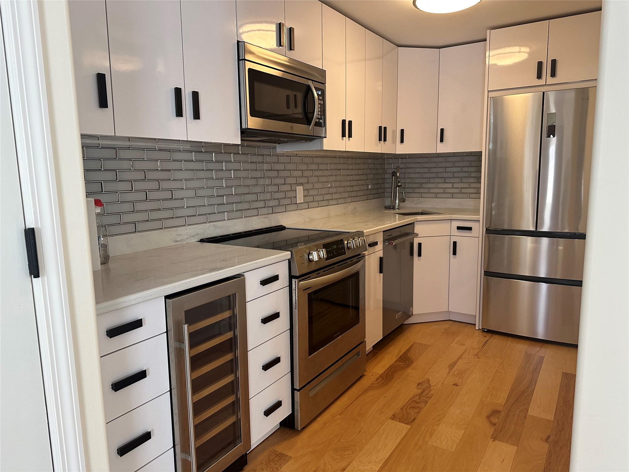 16-59 155th Street, Unit 1 Queens, NY 11357 - Photo 1 of 1 a kitchen with stainless steel appliances a stove a microwave refrigerator and cabinets