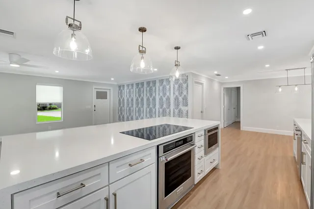 a kitchen with a sink dishwasher a refrigerator and white cabinets with wooden floor