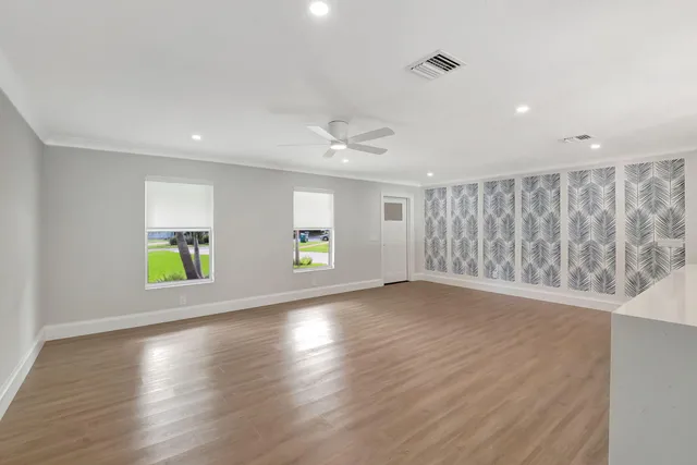 a view of an empty room with wooden floor and a window