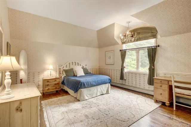 a bedroom with a bed a mirror on dresser and a window